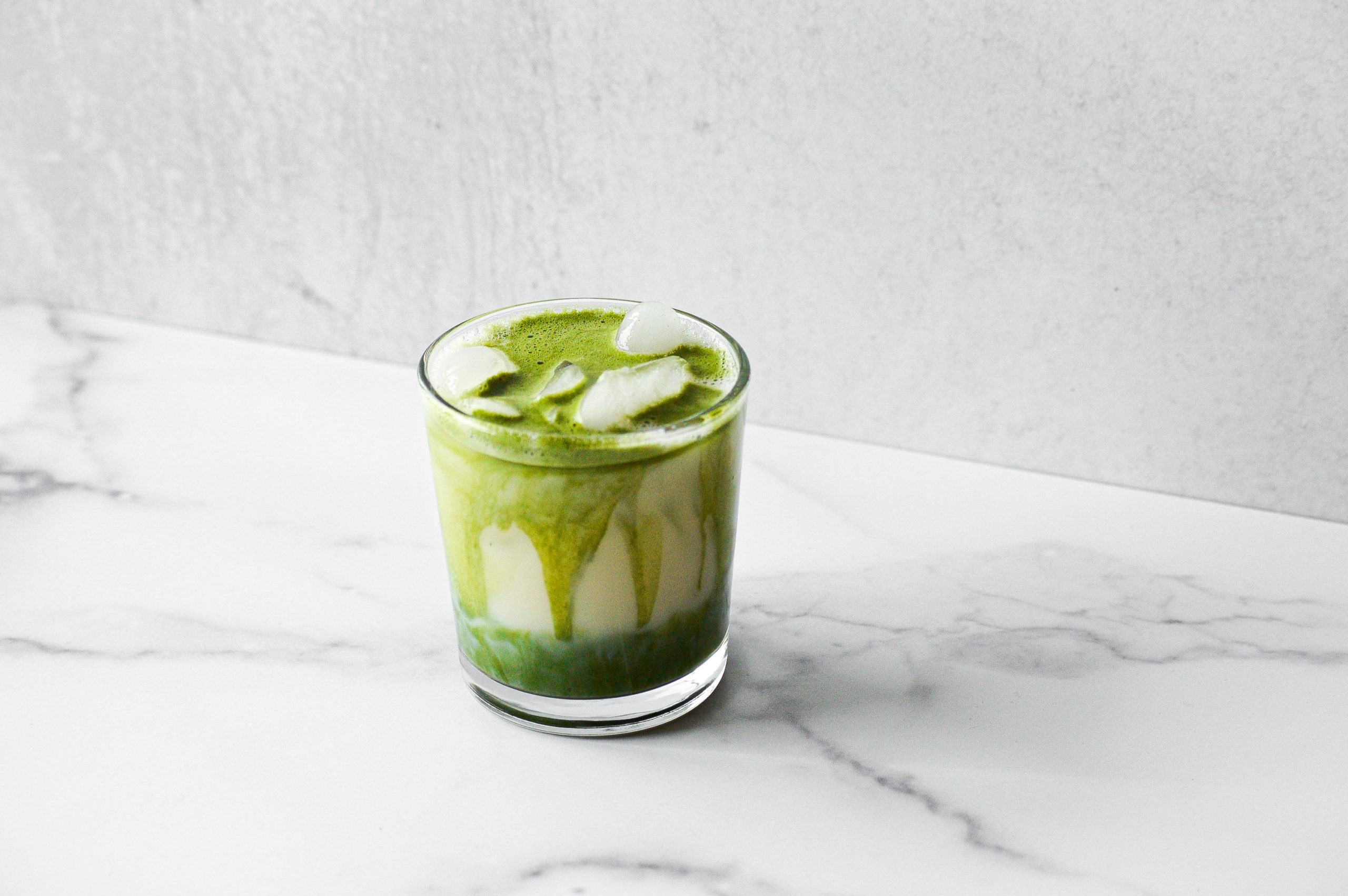 Iced matcha latte with marble and concrete background.